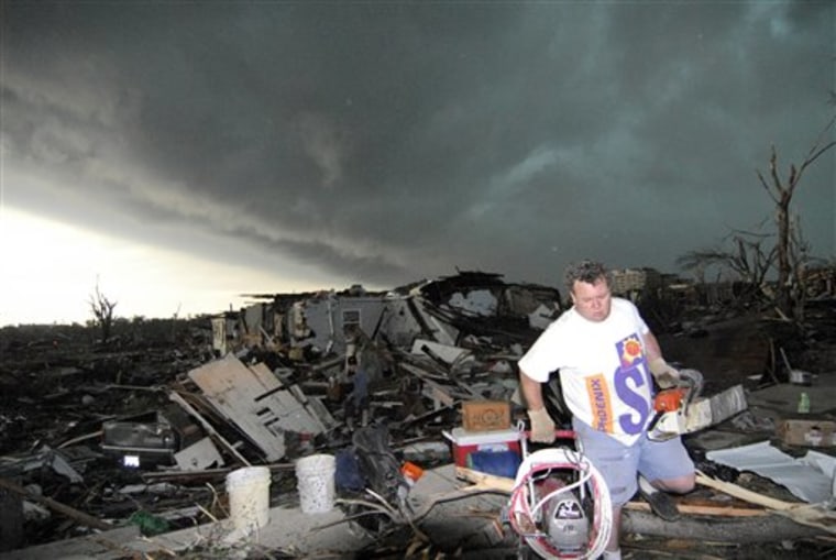 In this May 23 photo, Mark Siler carries salvaged items from the house of a friend following a devastating tornado in Joplin, Mo. The National Weather Service is kicking off an experiment next week with a new kind of tornado warning that's aimed to scare people into seeking shelter. 